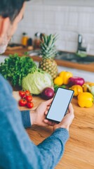 Man in blue sweater holding smartphone with blank screen in kitchen. Healthy cooking and meal preparation app concept. Recipe searching.