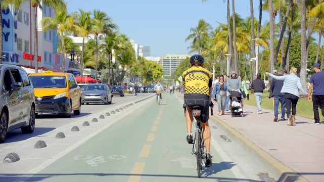 Following a man riding a bike in a bike lane on Ocean Drive Miami Beach 4k 60p