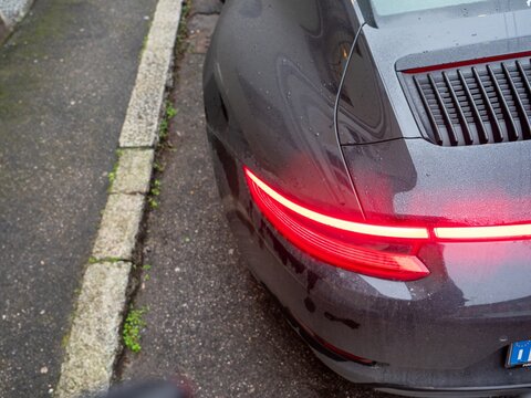 Porsche Carrera 4S rear lights illuminated on a wet asphalt street
