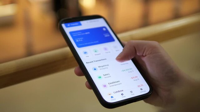 Modern financial management on the go. This close-up captures a woman securely accessing her bank account through a mobile app in a public setting, actively navigating its interface. It represents