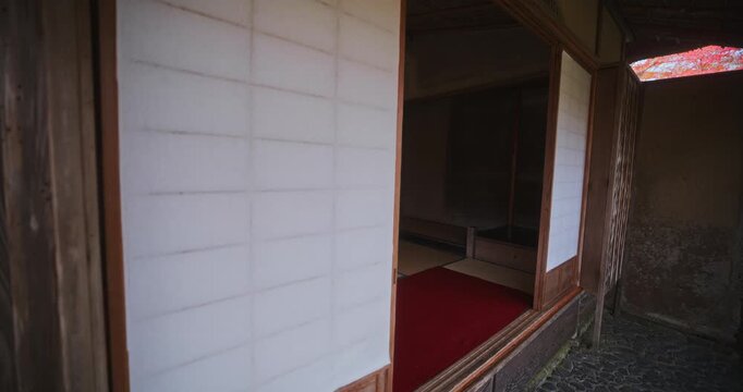 Steady cam outside of ancient Japanese home with sliding paper doors in slow motion