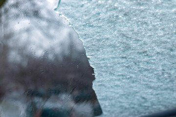 Closeup of a partially cleared car windshield covered in frost and ice, with blurred winter background. Seasonal concept for cold weather, driving, or safety.