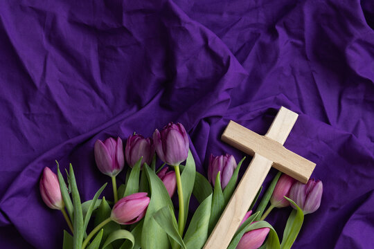 wood cross with pink and purple tulips on a purple background
