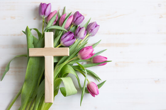 Wood cross on a bouquet of pink and purple tulips on a white background