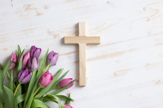 Wood cross with bouquet of pink and purple tulips on a white background