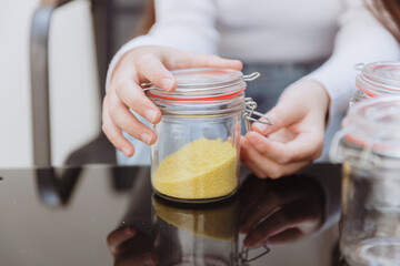 The girl closes the metal latch on the sugar jar.
