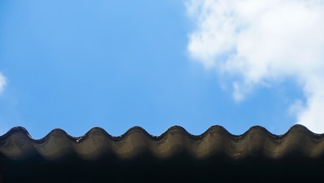 Corrugated asbestos roof corner against a clear blue sky