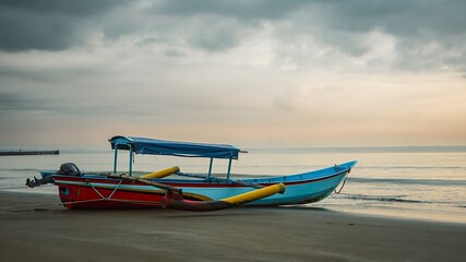 Traditional wooden boat on beach at sunset with dramatic clouds