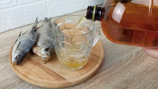 The bartender pours draft beer into a glass to go with dried fish