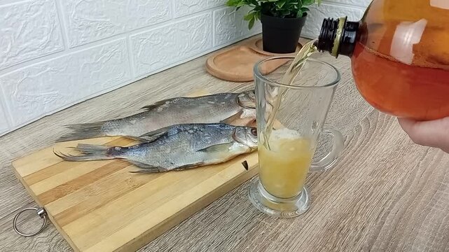 The bartender pours draft beer into a glass to go with dried fish