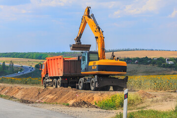 Obraz premium Dump truck and excavator are working on a suburban road