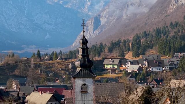 Cinematic Dolly Zoom of Stara Fuzina Church. Aerial Reveal of Snowy Mount Triglav in Clouds. Alpine Aesthetics with Winding Road and Julian Alps Backdrop. Slovenia Mountain Village HDR 4K