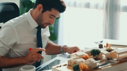 Top view of project manager writing house idea on sticky notes while looking plan at tablet. Aerial...