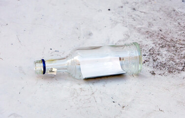 Used dirty empty glass bottle litter on city street pavement