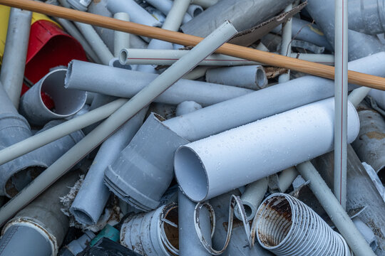 Pile of discarded gray plumbing tubes and plastic pipes