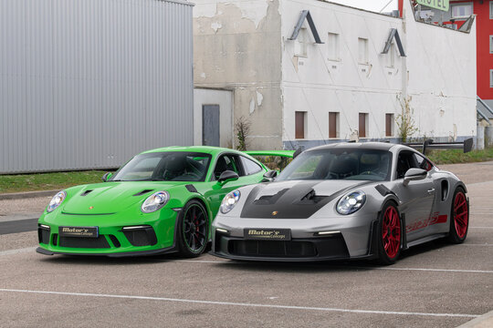 Metz, France - October 16th 2025 : View on a grey Porsche 992 GT3 RS Weissach Package finished in Argent GT with the Pyro red rims and a green Porsche 991 GT3 RS finished in Lizard green on a street.
