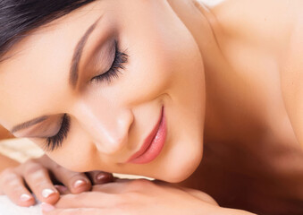 Beautiful, young and healthy woman on bamboo mat in spa salon is having hot stone massage. Isolated on white. Spa, health and healing concept.