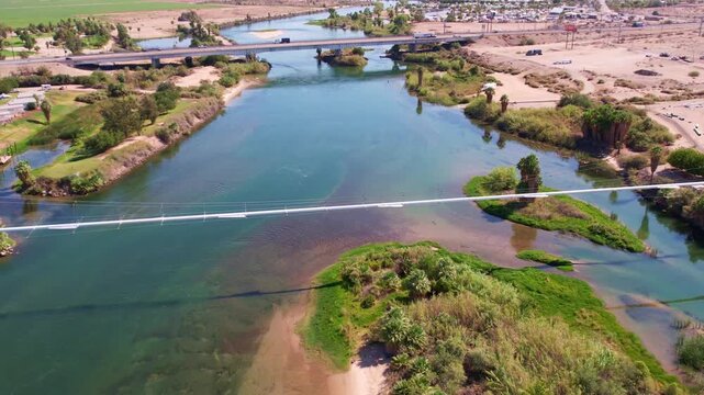 Aerial view of a utility pipeline bridge crossing the Colorado River in a desert landscape.