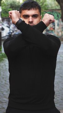 Vertical: A young man clearly shows disagreement using expressive arm gestures and body language. His firm posture and serious face communicate refusal, opposition, and strong personal opinion.