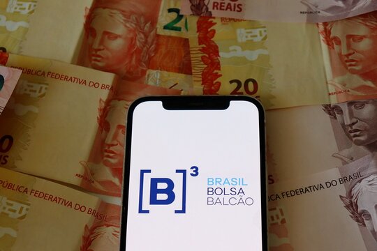 Salvador, Brazil - February 12, 2026: B3 (Brasil Bolsa Balc&atilde;o) logo on a smartphone screen over Brazilian Real banknotes. Brazilian Ibovespa (Bolsa de Valores). 