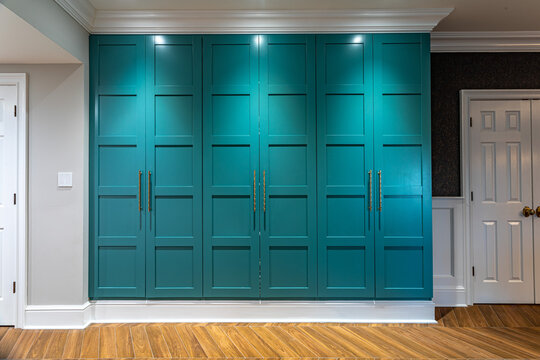 Modern teal built in cabinetry with brass handles and wood flooring