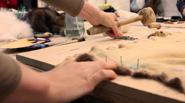 Close up of a furrier hands processing a mink pelt with a special tool in a traditional workshop. Detailed manual work in the fur industry, showing craftsmanship and preparation of natural pelts 