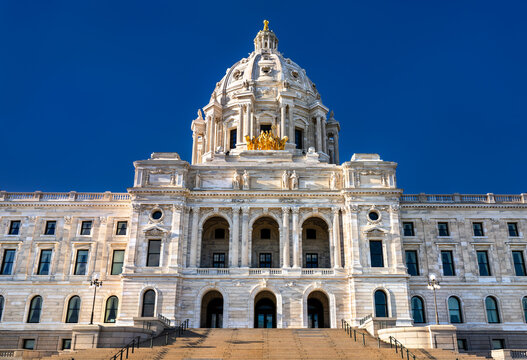 Minnesota State Capitol building stands in Saint Paul, USA. Renaissance Revival architecture features a white marble dome and golden quadriga statue under a blue sky