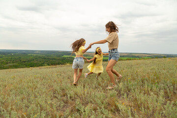 Mom and daughters having fun on the meadow to have a picnic to enjoy the summer day