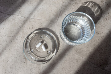 Obraz premium White pill and glass with water stay on the marble table.