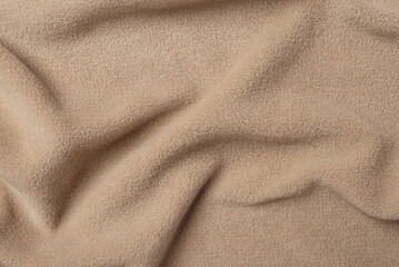 Fleece beige fabric texture background with gentle folds, top view © Anna