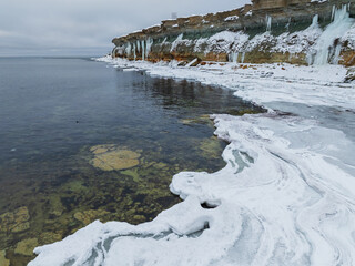 High angle drone view of the Baltic Sea starting to freeze near the steep limestone cliffs of the Pakri peninsula.