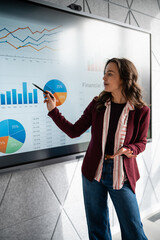 Woman presenting financial data graphs on interactive screen