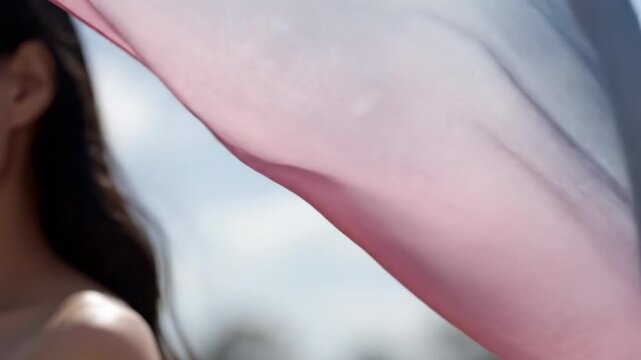 Woman's profile with flowing transgender pride flag against a bright sky