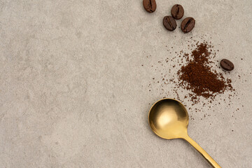 Ground coffee in spoon with coffee beans on beige background, top view
