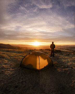 A man wild camping in the Peak District of England during an amazing sunrise