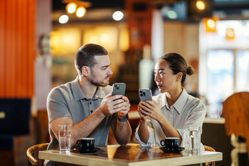 Couple distracted by smartphones on a date in cafe