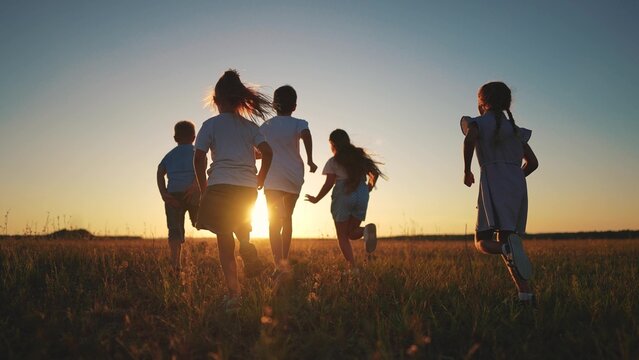 children running in the park silhouette. people in park. children a kid together run in park at sunset silhouette. group of lifestyle children run. happy family and little baby child summer
