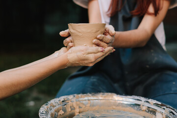 Handmade clay bowl is held after removal from the wheel. Ceramic pot reflects artistry, patience,...
