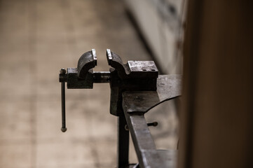 Close-up of vintage metalwork vice on workbench in workshop, industrial tools for craftsmanship and repairing, muted background © Олег 21