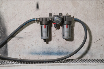 Industrial water filtration system with pressure gauge and pipes mounted on a textured wall