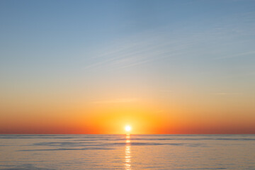 Naklejka premium Dramatic Sunset over Calm Ocean Horizon with Vivid Orange and blue Sky high resolution photo with copy space.