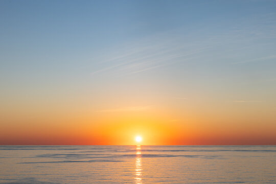 Dramatic Sunset over Calm Ocean Horizon with Vivid Orange and blue Sky high resolution photo with copy space.