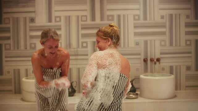 Friends relaxing and enjoying a joyful and foamy traditional hammam spa treatment