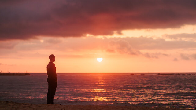 Man finding solitude on beach watching sunset