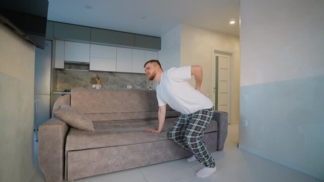 Man hurting back lifting sofa at home