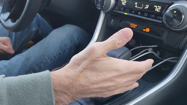 Male hand moves the transmission selector lever to reverse gear. The scene focuses on driver control, vehicle operation, and interior detail of a modern automobile.