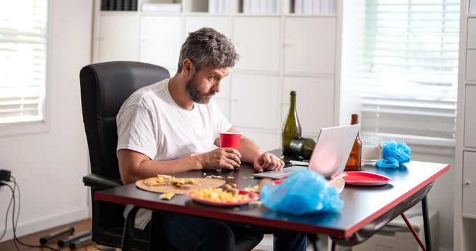 Tired employee work in home office after party. Mature businessman office party mess. Sleepy office worker has hangover. Man at home with laptop. Man having morning hangover. Messy hangover scene