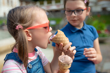 Two sisters sharing waffle cone ice cream together in sunny city park, close-up of kids hands and faces, sweet summer dessert moment