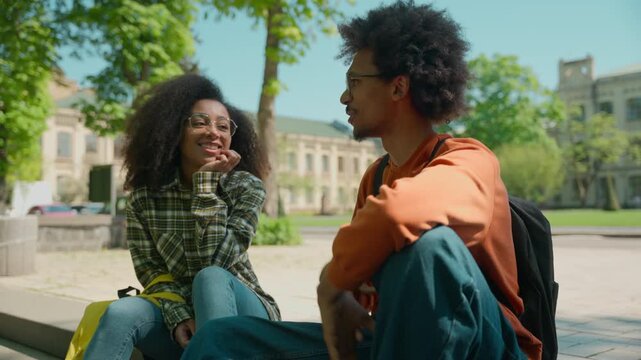 Two African American female male students friends talking smiling university outdoors ethnic multiracial woman man girl guy girlfriend boyfriend in city communicate college study teenagers classmates