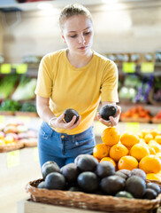 Fototapeta premium Teenage girl buyer choosing fresh avocado in vegetable shop